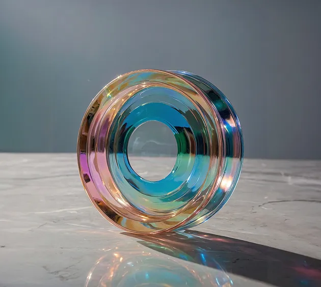 Transparent, multicolored glass ring sculpture placed on a marble surface casting a shadow.